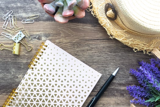The Flat lay of vintage feminine summer concept with pink spiral notebook, beach hat, clips and decorative flowers. photo