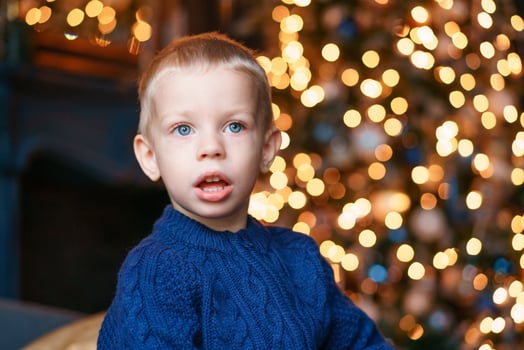 Portrait boy on winter evenings against background christmas lights. Excited photo