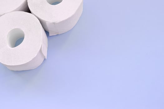 Coronavirus pandemic panic shopping concept. Few new toilet paper rolls on light blue background. Minimalistic flat lay composition with copy space photo