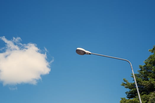 Modern electricity lamp post with blue sky and cloud as background. Steel street light or lantern on pole in the daytime are conceptualized in industrial, technological, and urbanize photo