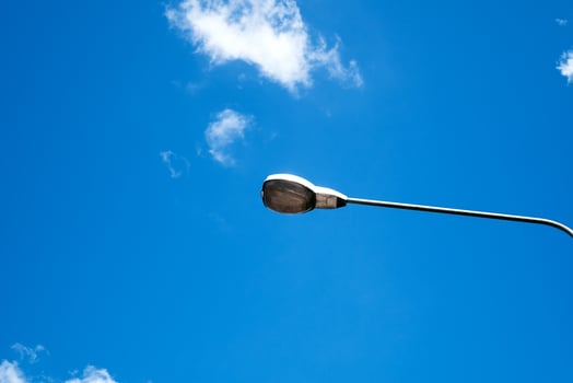 Modern electricity lamp post with blue sky and cloud as background. Steel street light or lantern on pole in the daytime are conceptualized in industrial, technological, and urbanize photo