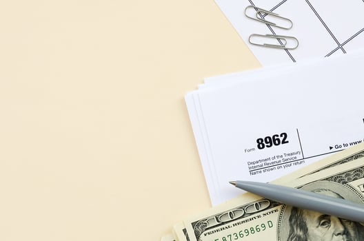 IRS Form 8962 Premium tax cerdit PTC blank lies with pen and many hundred dollar bills on calendar page photo