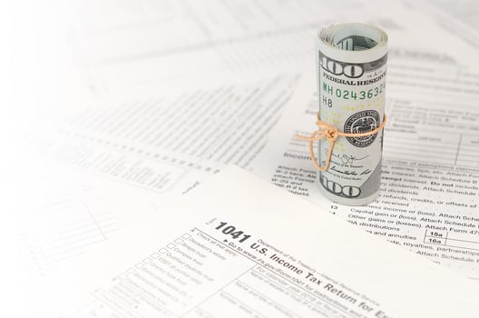 1041 U.S. Income tax return for Estates and Trusts form with roll of american dollar banknotes photo