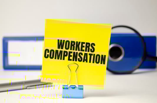 Workers compensation on yellow sticker and blue file folder photo