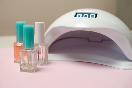 UV diode lamp lights for nails and set of cosmetic nail polish for manicure and pedicure on pastel background photo