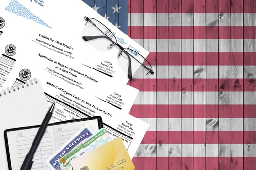 I-130 Petition for alien relative, I-485 Application to register permanent residence or adjust status and I-864 Affidavit of support under section 213A of the INA forms lies on table photo