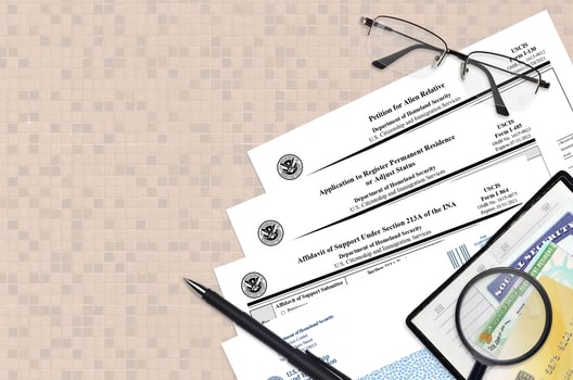 I-130 Petition for alien relative, I-485 Application to register permanent residence or adjust status and I-864 Affidavit of support under section 213A of the INA forms lies on table photo