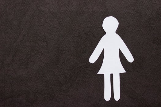 Silhouette of a woman in dress of white paper, cut by hand. On right side of the photo on black background. With copy space