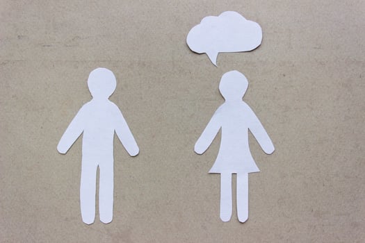 The silhouettes of a man and woman in a dress made of white paper, cut by hand. With speech-bubble over woman. photo