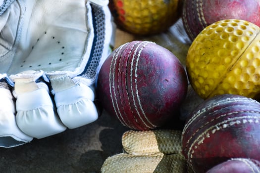 Training cricket sport equipments on floor, leather ball, gloves and bat, soft and selective focus on ball. photo