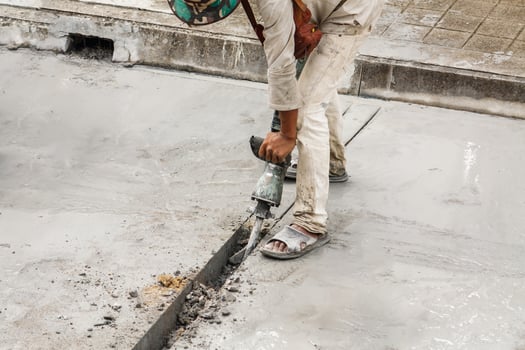 Construction worker using jackhammer drilling concrete surface photo