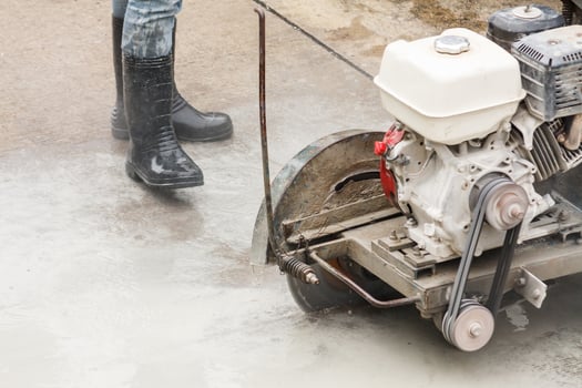 Worker using diamond saw blade machine cutting concrete road at construction site photo