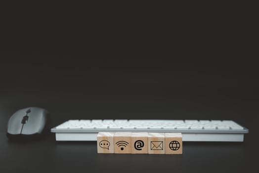 Online business communication symbols contact us or e-mail address marketing concept on wooden cubes with computer keyboard background. photo