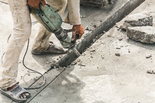 Construction worker using jackhammer drilling concrete surface photo