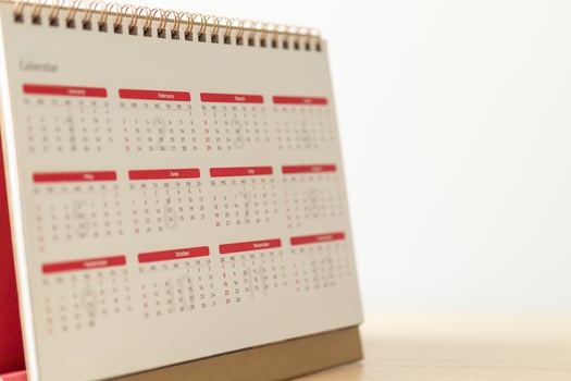 Calendar page close up on wood table with white wall background business planning appointment meeting concept photo