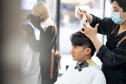 Asian men Hair stylish with customer while do hair cut and wearing surgical face mask while styling hair for client. Professional occupation, beauty and fashion service new normal photo