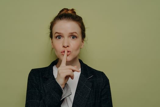Beautiful young woman in casual wear asking for silence photo