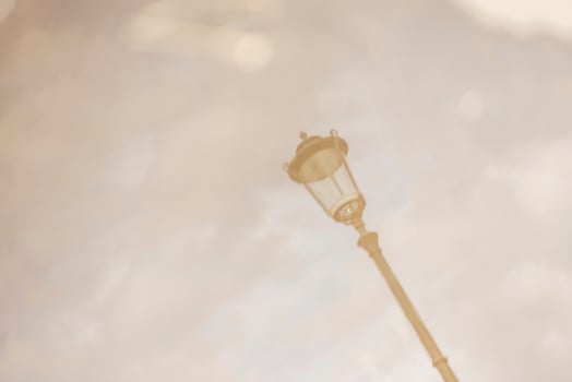 Street lamp. Reflection in a puddle against a cloudy sky in cloudy weather. Blurry image photo
