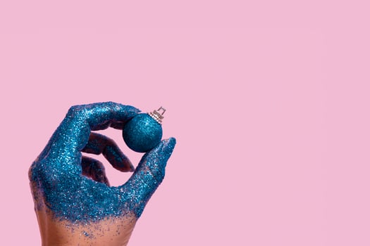 Creative Christmas concept of female hand with blue glitter and Christmas ball on color background photo