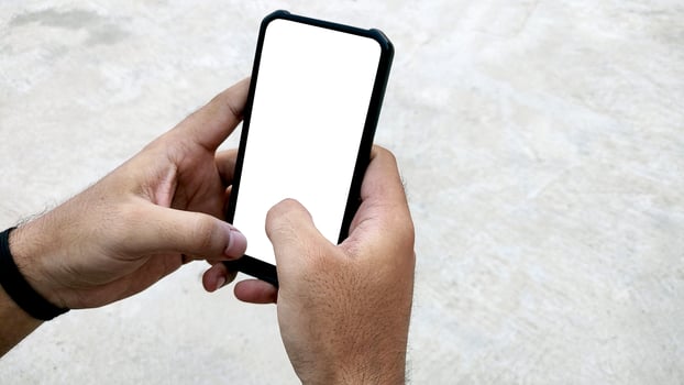 Man holding smartphone with blank screen on white background, closeup of hand. Space for text photo