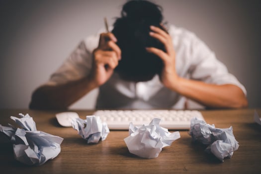 Businessman sitting with head in hands at desk covered crumpled papers. Office worker tired of too much difficult unproductive work. Stressed male entrepreneur has no idea what to do with problem photo