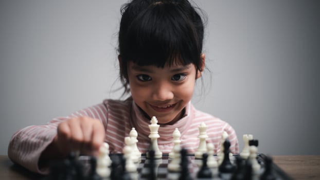 little girl playing a game of chess on a chessboard. photo