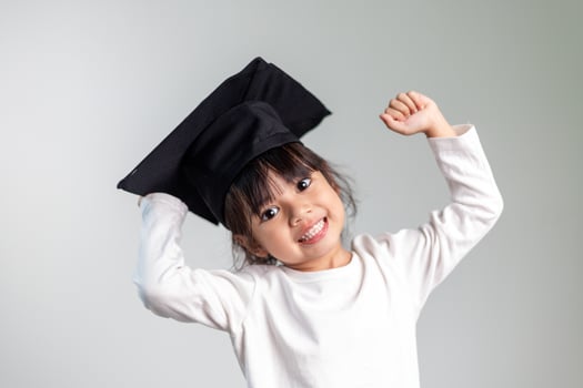Happy Asian school kid graduate in graduation cap photo