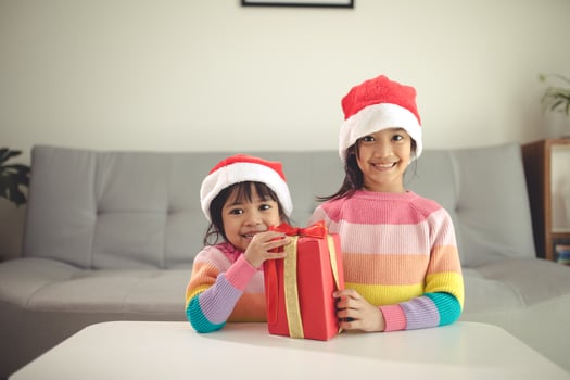 Merry Christmas happy sibling girls with a gift at home photo