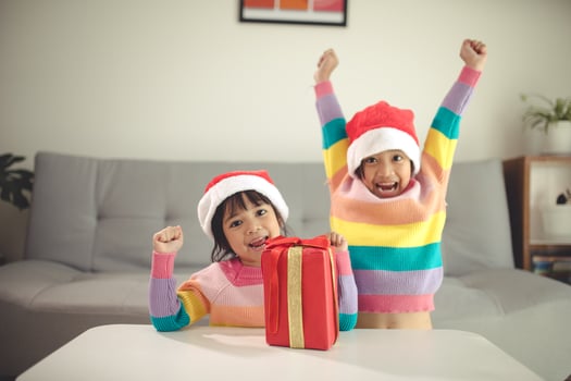 Merry Christmas happy sibling girls with a gift at home photo