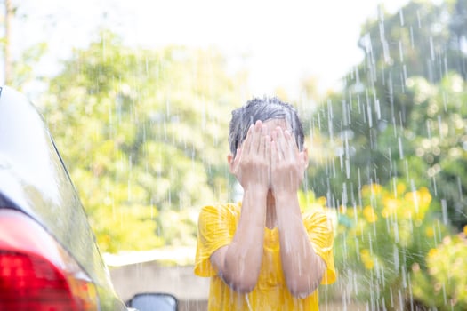 Happy Asian girl washing car on water splashing and sunlight at home photo