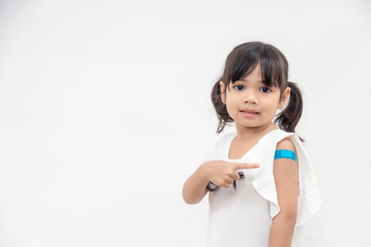 Asian little girl showing his arm after got vaccinated or inoculation, child immunization, covid delta vaccine concept photo