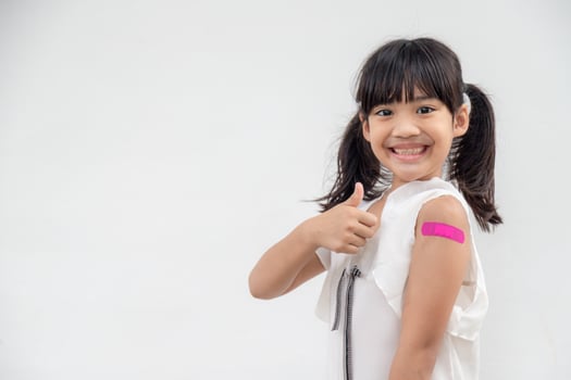 Asian little girl showing his arm after got vaccinated or inoculation, child immunization, covid delta vaccine concept photo