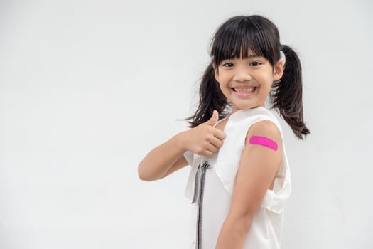 Asian little girl showing his arm after got vaccinated or inoculation, child immunization, covid delta vaccine concept photo