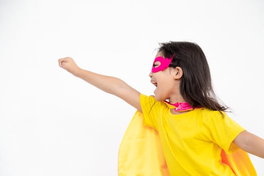 Funny little girl playing power super hero over white background. Superhero concept. photo