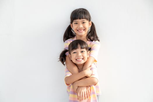 Cute happy Asian siblings hugging cuddling feeling love and connection, smiling kid girl sister embracing little girl sister on white background, 2 children good relationships photo