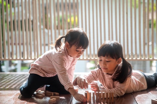 two Asian girls playing wooden stacks at home photo