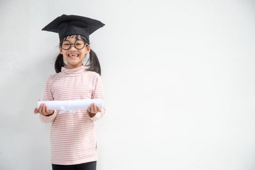 Happy Asian school kid graduate in graduation cap photo