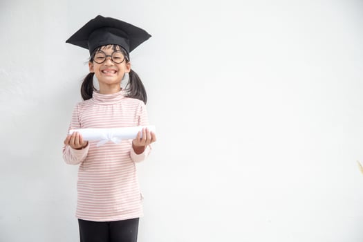 Happy Asian school kid graduate in graduation cap photo