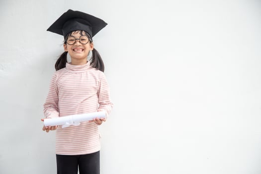 Happy Asian school kid graduate in graduation cap photo