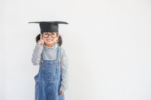 Happy Asian school kid graduate thinking with graduation cap photo