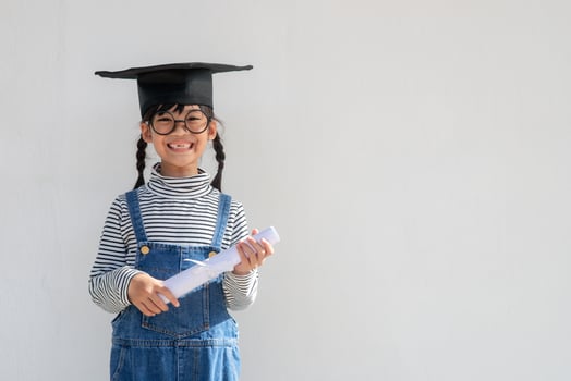 Happy Asian school kid graduate in graduation cap photo