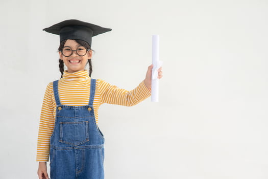 Asian Little girl wearing a graduation cap and holding diploma on white background photo
