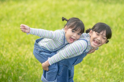Asian Little girl with elder sister at a park riding on her back photo
