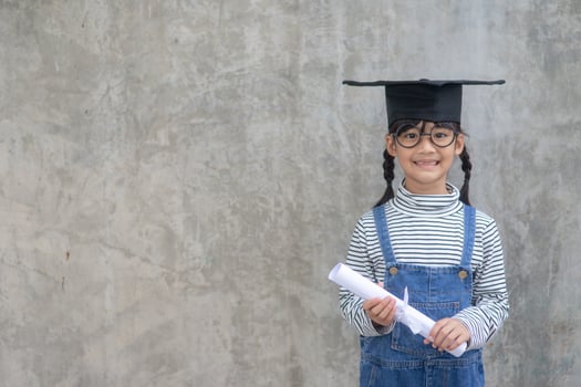 Happy Asian school kid graduate in graduation cap photo