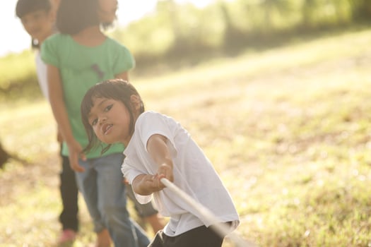 Children playing tug of war at the park on sunsut photo