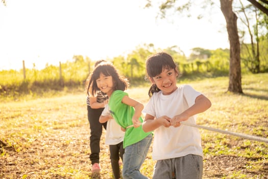 Children playing tug of war at the park on sunsut photo
