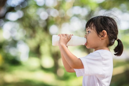 Cute asian little child girl is drinking a milk, soft focus photo