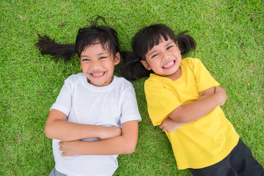 Closeup of happy asian children lying on the green grass photo