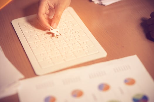 Hand places a piece of the white jigsaw puzzle to full field the gap of the jigsaw to make the puzzle completely finish, represent businessman or someone finishes the job.vintage color photo