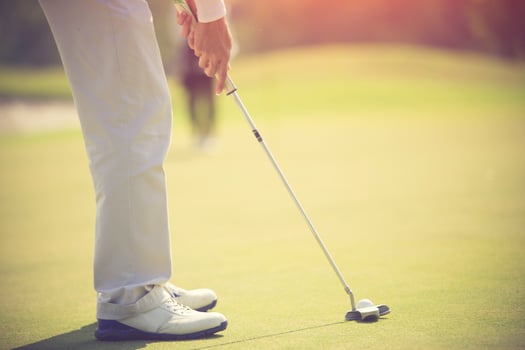 Golf player at the putting green hitting ball into a hole photo